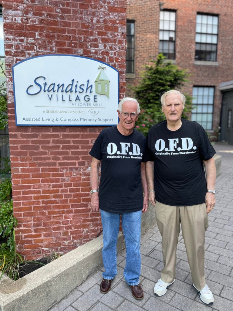 Two Dorchester natives pose smiling in front of Standish Village Assisted Living.