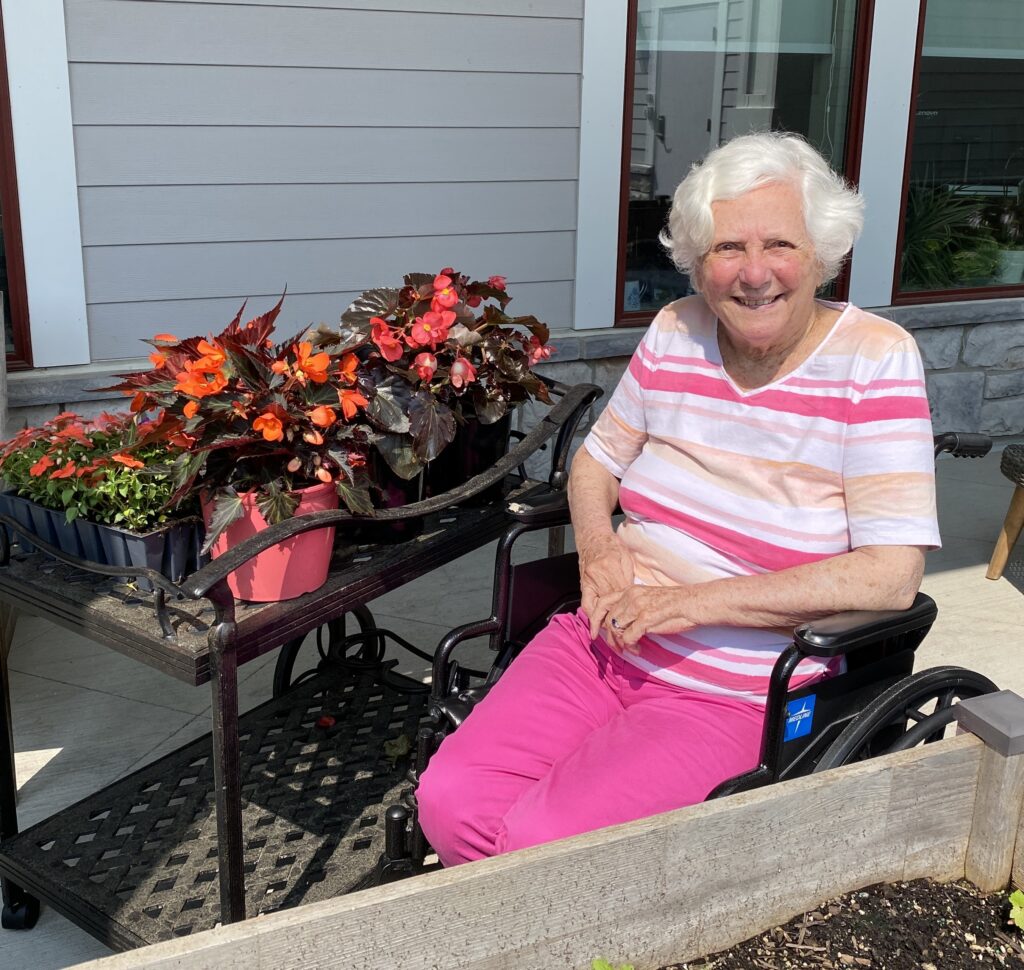 Woman sitting next to garden bed with flowers