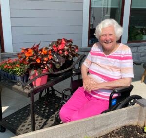Woman sitting next to garden bed with flowers