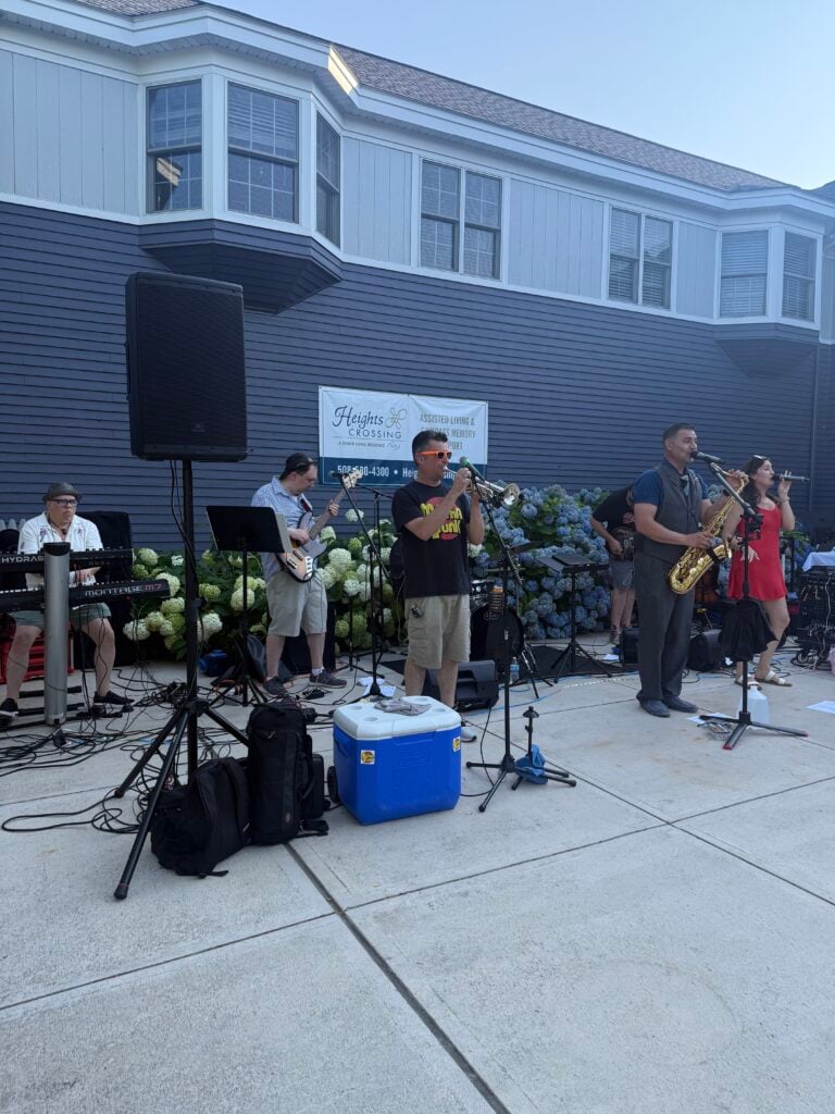 Bands plays jazz and funk music outside in front of an assisted living community
