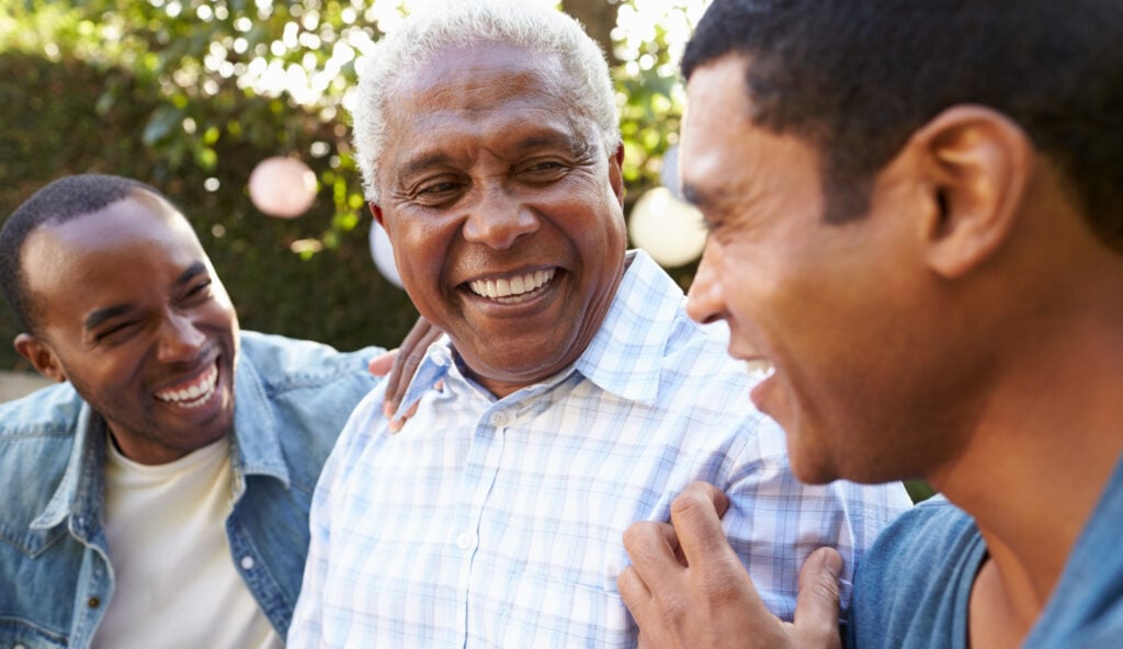 An older gentleman smiles with his two sons at Nashoba Park Assisted Living.