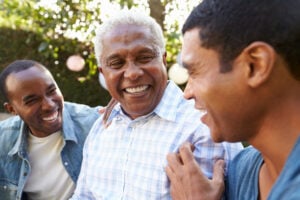 An older gentleman smiles with his two sons at Nashoba Park Assisted Living.